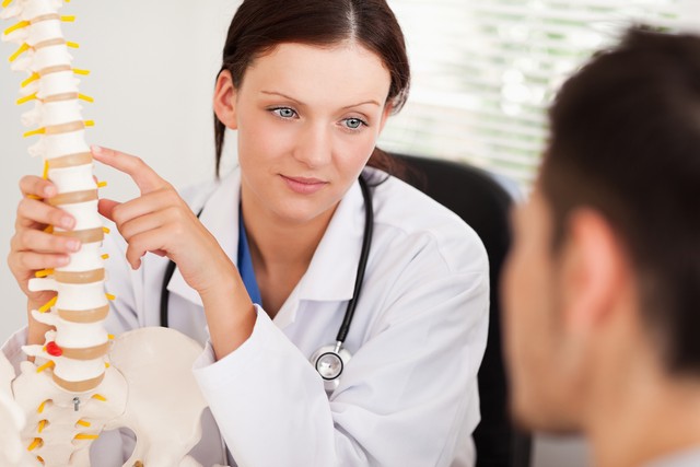 A female doctor is showing her patient a spine